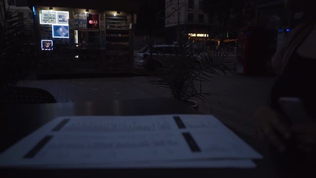 Girl pointing at menu at outside cafe with people walking in the background