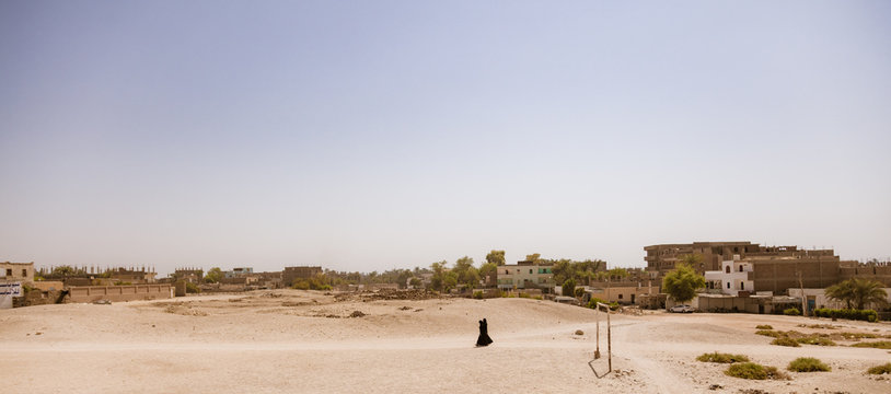 Two people walking through a village
