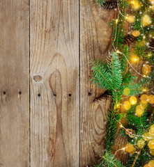 Christmas background with fir tree branches and lights on wooden board