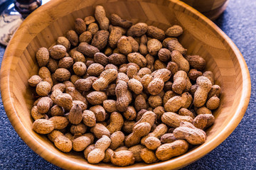 A lot of peanuts are a tasty and fresh snack. Natural and healthy nuts are full of vitamins and oils. They lie in a wooden bowl in the store and on the market.