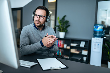 Attractive male support center agent with headset on talking to client.