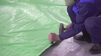 men's hands preparing eyelets on a plastic tent
