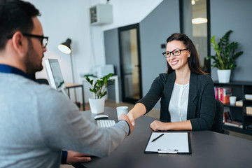 Business people shaking hands in modern office. Businesss agreement, partnership or job interview.
