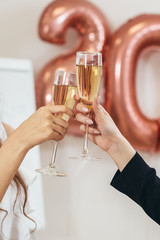 Two women clink glasses during holiday. Hands close up. Celebration.