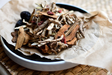Chinese traditional medicine script. Herbal tea with jujubes, goji berries, gingseng roots and others on neutral background.