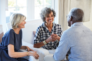 Group of multiethnic senior friends visiting and talking in the living room at home