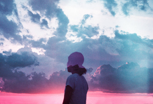 Girl looking out at a cloudy sunset sky