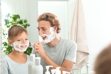 Father and son shaving together in bathroom