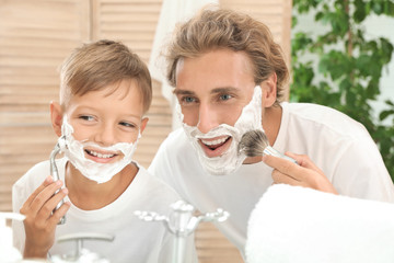 Father and son shaving together in bathroom