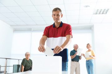 Man putting ballot paper into box at polling station