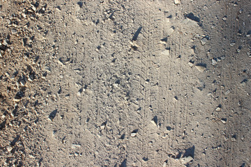 Traces markings and stones on dirt road background shadows