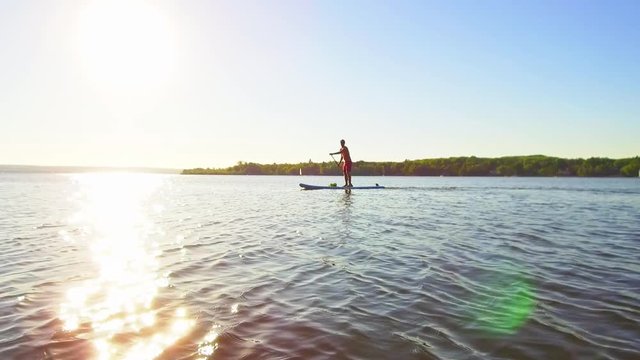 Standup Paddler auf dem See beim Sonnenuntergang