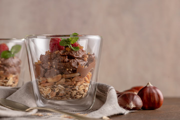 Glass cups of chocolate and chestnuts mousse with roasted almonds and oats decorated with raspberry...