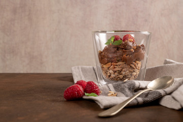Glass cups of chocolate and chestnuts mousse with roasted almonds and oats decorated with raspberry...