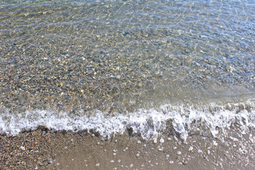 Crystal clear sea water pebbles beach wave swash