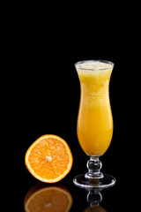 Closeup glass of fresh orange juice with ice isolated at black background.