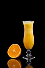 Closeup glass of fresh orange juice with ice isolated at black background.