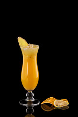 Closeup glass of fresh orange juice with ice decorated with ginger and orange chips isolated at black background.