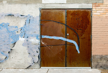 Rusted door and wall with blue paint splatter