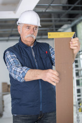 senior builder measures the angle wood