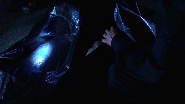 Coroner unzipping body bag, looking at victim face, investigation of woman death