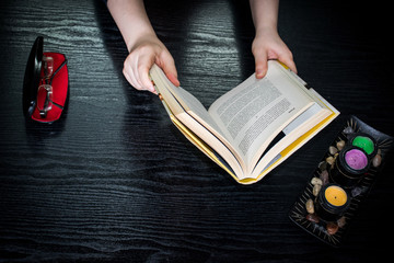 Closeup of a Girl sitting and holding a book and reading at home on a black table , she is learning knowledge and gaining information