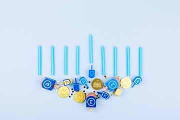 Blue background with menora made of dreidels and chocolate coins. Hanukkah and judaic holiday concept.