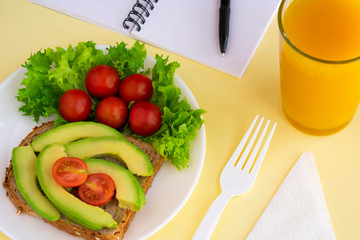 Healthy vegetarian snack with avocado, cherry tomatoes, lettuce leaves, glass of juice. Top view. Diet or weight control concept.