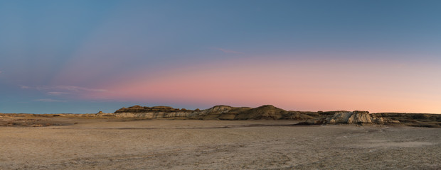 Panorama of the desert landscape and hills of the Bisti Badlands of New Mexico at sunset under a...