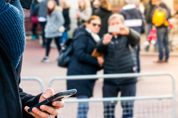 Closeup of a Young boy using smartphone mobile in evening sunny day in crowded public place , wearing black jacket. business man using smartphone