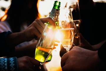 Crop people clinking glasses against bright sun