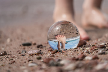 Boy feet and glass ball on the beach