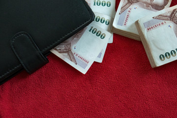 black wallet and thai a lot of banknote on red background, banking concept