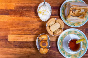 Closeup of top View of Fresh morning breakfast with , tea, funny face toast, cake, yogurt , tasty biscuits on yellow wooden table, dairy products.