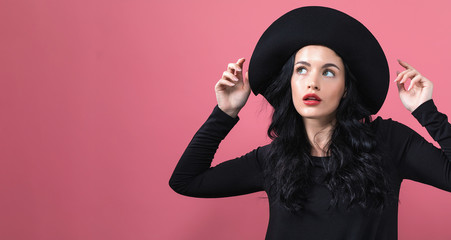 Beautiful young woman in a fashionable coat on a pink background