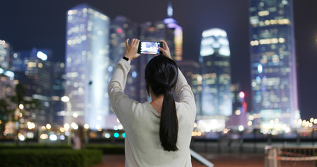 Woman take photo on cellphone in Hong Kong at night