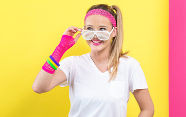 Woman in 1980's fashion with shatter shade glasses on a split yellow and pink background