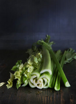 Celery rests on a wooden surface.