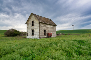 abandoned house in field with windmill