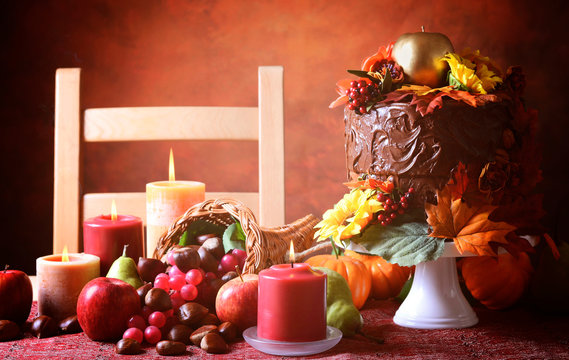 Thanksgiving Fall table setting with Autumn theme chocolate cake, cornucopia and candles.