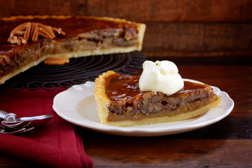 Traditional Thanksgiving individual serving of pecan pie on dark wood rustic wood table and background. 