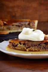 Traditional Thanksgiving individual serving of pecan pie on dark wood rustic wood table and background, with copy space. . 