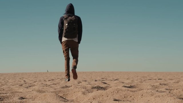 Man walking alone in the sunny desert near Dubai backpack tourist alone