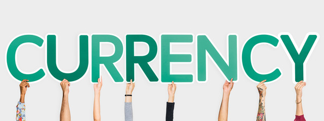 Hands holding up green letters forming the word currency