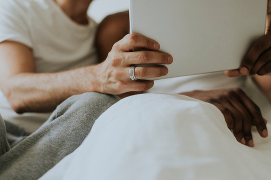 Gay couple using a tablet in bed