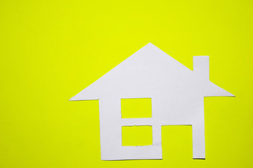Concept of house in paper on yellow background. Horizontal composition. Top view.