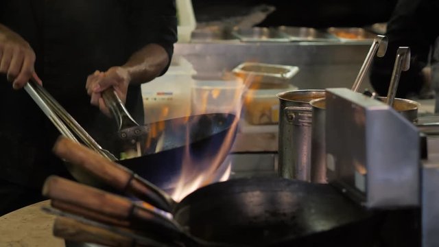 Chef is stirring vegetables in wok noodles fire flambe asia kitchen chinesse pan pasta seafood