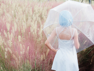 Rear view of beautiful young Chinese woman wearing white halter dress and holding transparent...