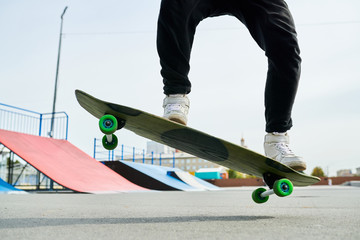 Low section portrait of contemporary young man doing skateboard tricks outdoors in extreme park, copy space