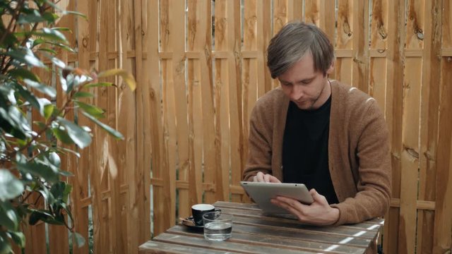 portrait of small business owner at his coffee shop using tablet pc airpods